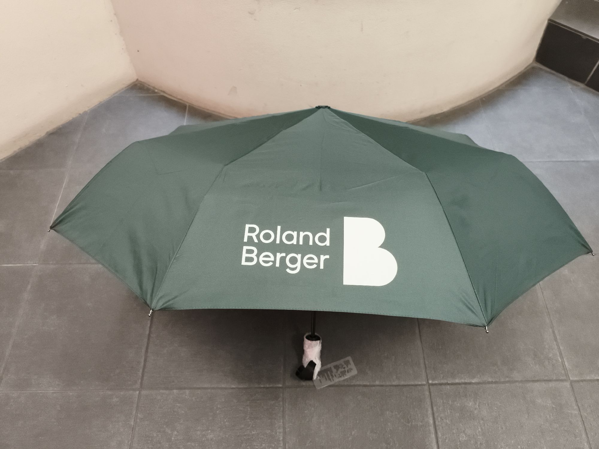 green umbrella branded with roland berger logo for an event giveaway