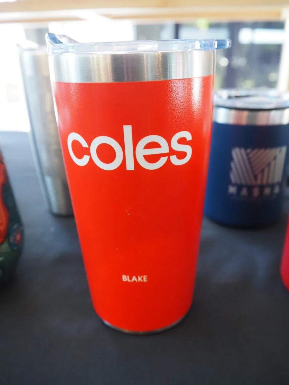 orange insulated tumbler with coles and blake text printed