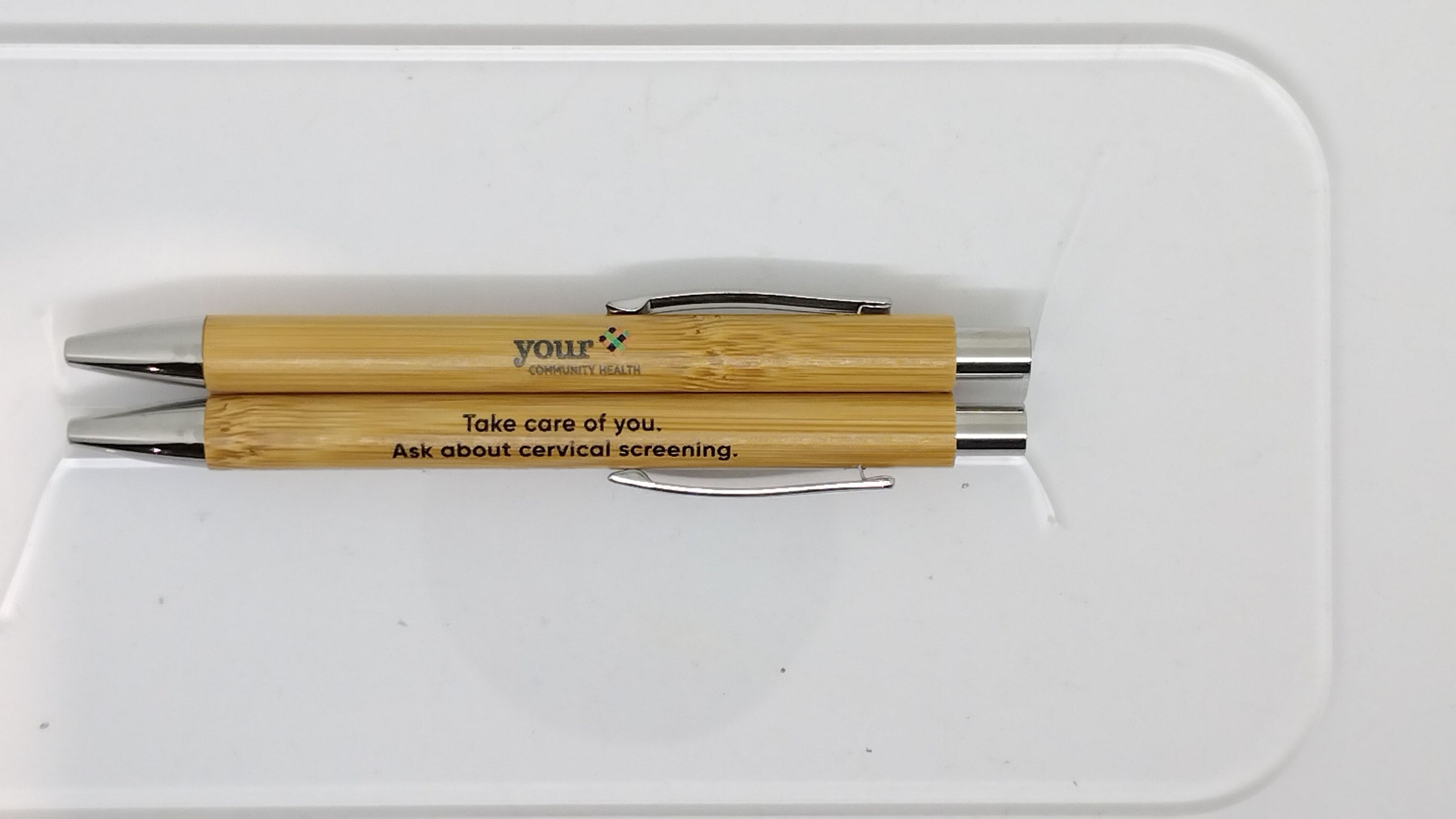 two eco-friendly pens with Your Community Health logo