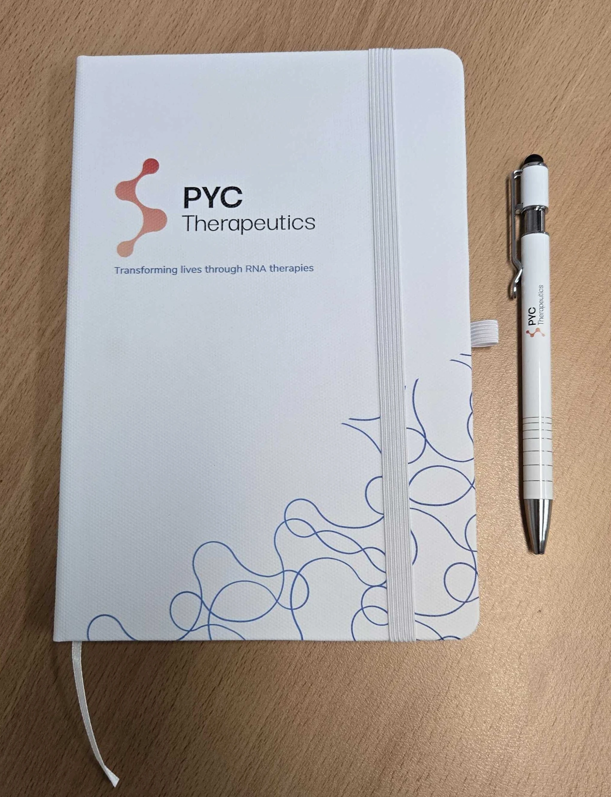 white notebook and pen set branded with PVC Therapeutics logo