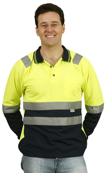 Smiling man in a yellow and navy reflective safety shirt, hands behind his back.