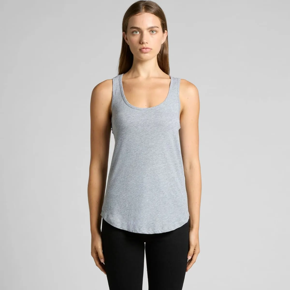 Woman wearing a gray tank top and black pants, standing against a plain background.