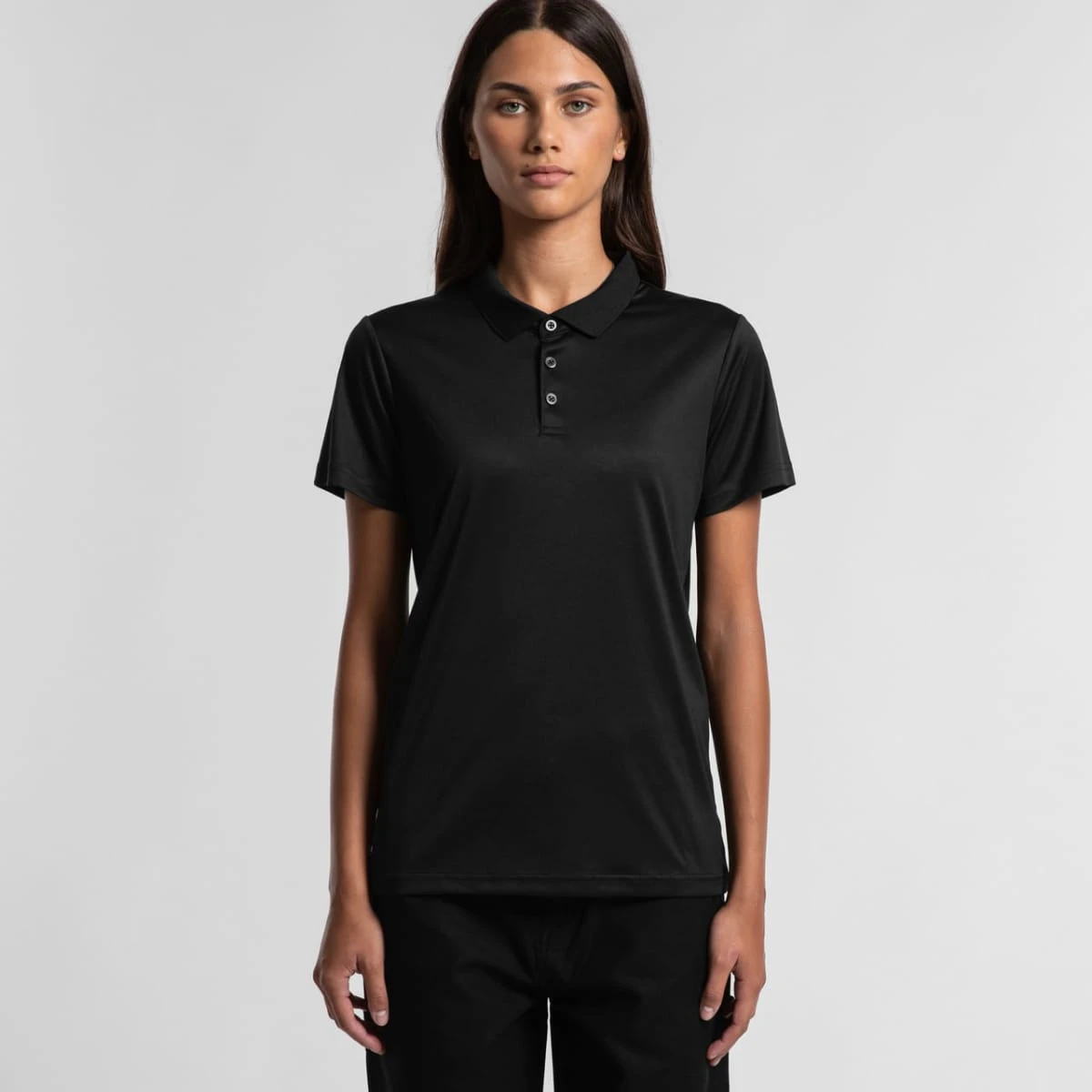 4425_wos_work_polo_main__59878.1685663850.1280.1280 Woman wearing a black short-sleeve polo shirt and black pants, standing against a gray background.