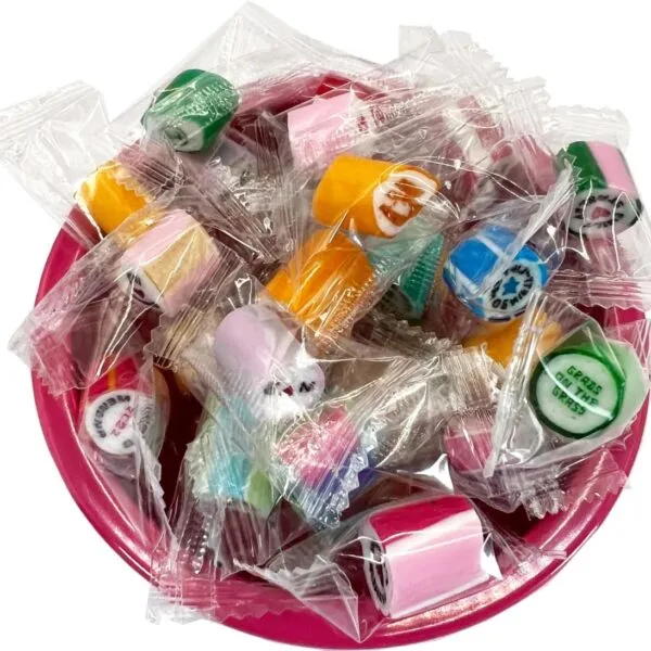 A pink bowl filled with assorted colorful hard candies in clear wrappers.