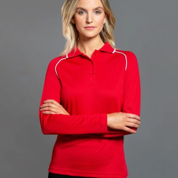 Woman in red long-sleeve polo stands against a gray background, arms crossed.