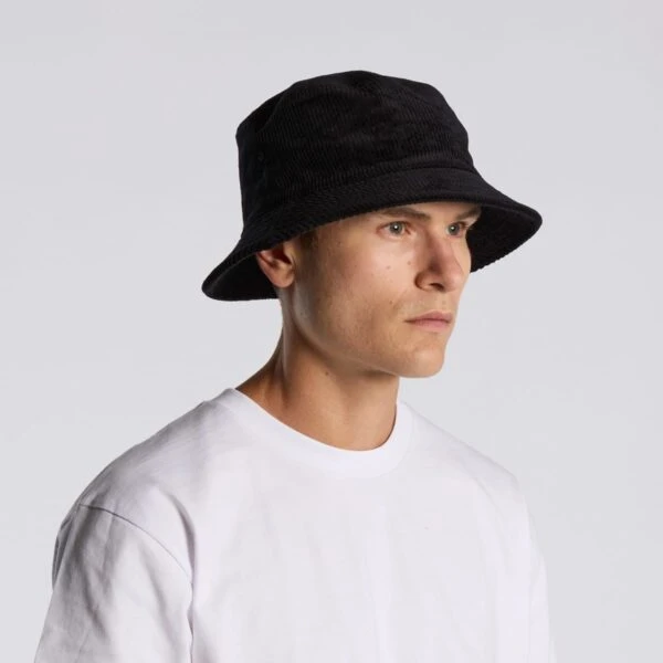 Person in a white shirt wearing a black bucket hat against a plain light background.