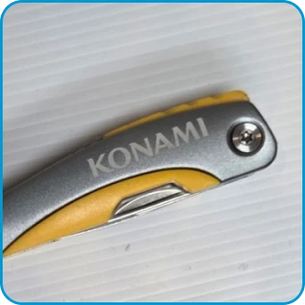 A close-up of a folding knife handle with the word KONAMI engraved on it.