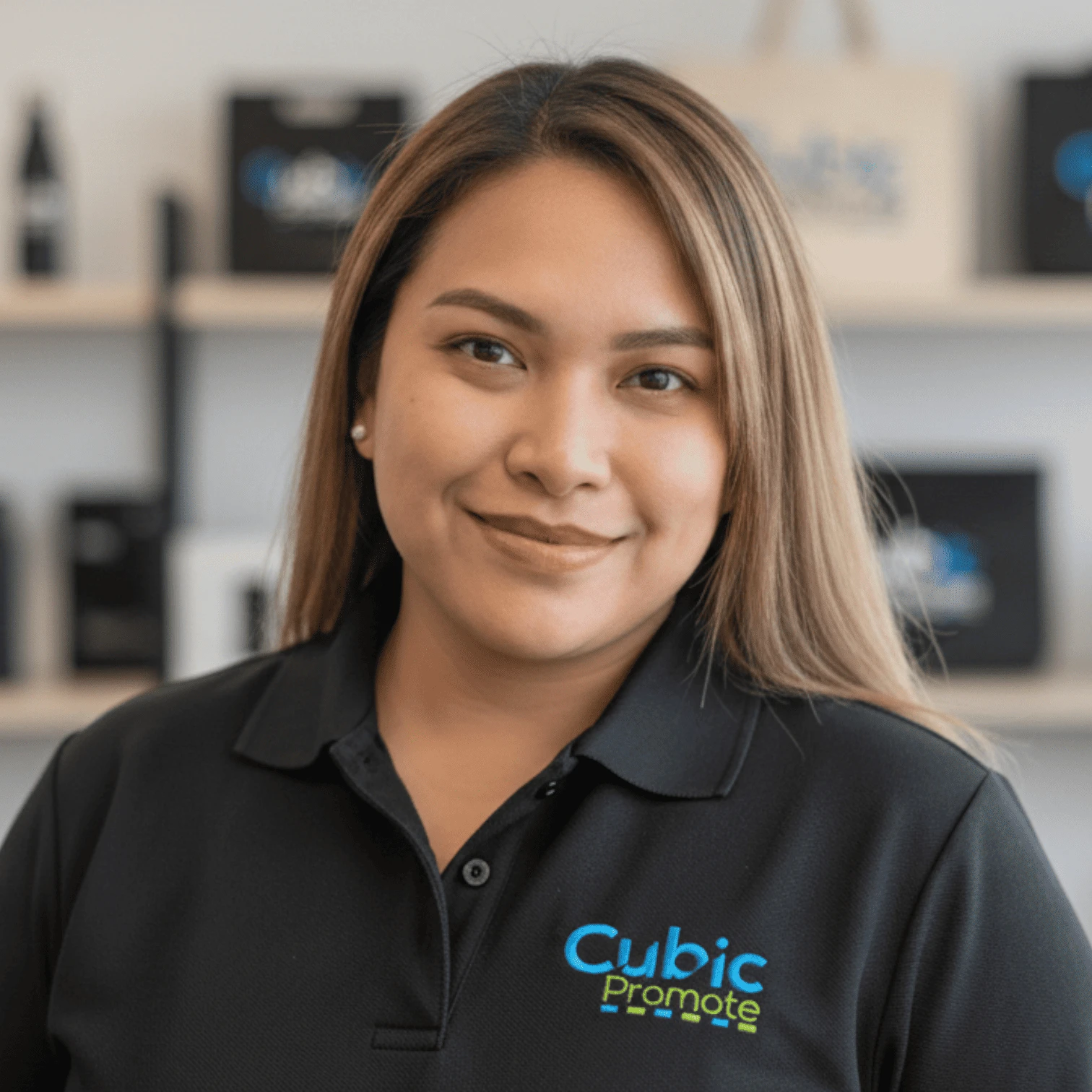 Woman smiling in a black Cubic Promote polo shirt, ready for a meet the team office event.
