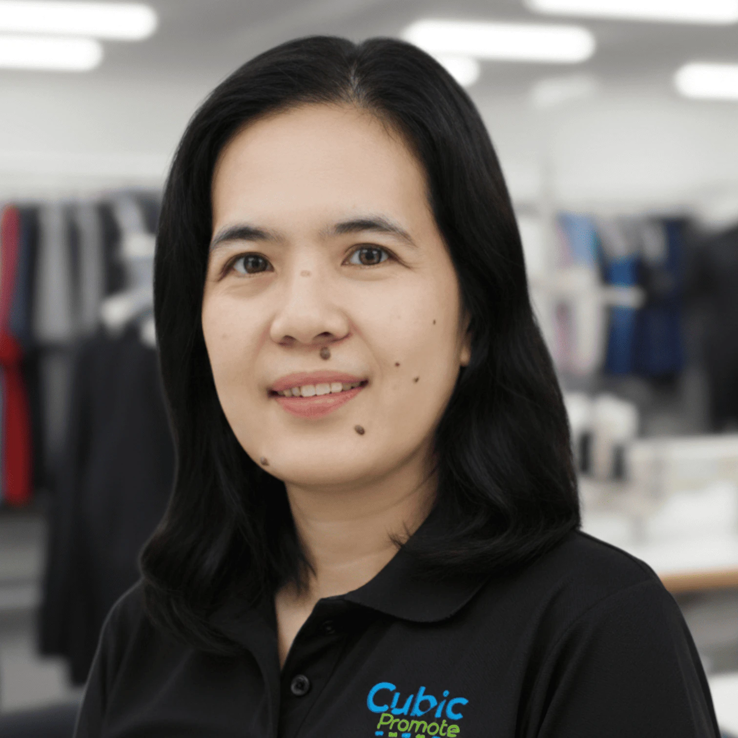 Meet the team: Woman with dark hair in a black Cubic Promote shirt, in a clothing store.
